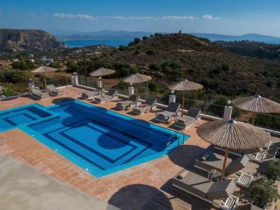 Piscine avec transats et parasols sur une terrasse avec vue sur les collines et la mer