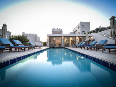 Piscine extérieure moderne avec chaises longues bleues et parasols blancs sous un ciel clair.