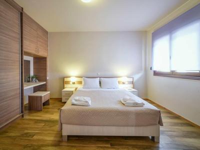 Chambre d'hôtel lumineuse avec lit double, tables de chevet, fenêtre et parquet.