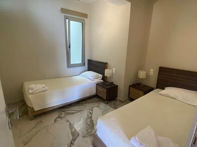 Chambre d'hôtel avec deux lits simples, table de nuit et fenêtre avec rideaux.