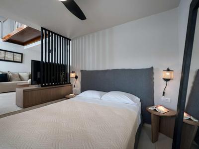 Chambre moderne avec grand lit, tête de lit grise et éclairage indirect