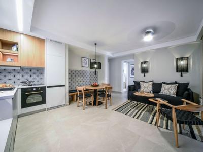 Cocina abierta moderna con mesa de comedor y área de descanso acogedora en tonos neutros.