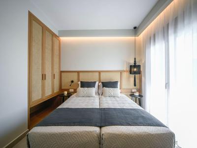 Habitación de hotel moderna con dos camas individuales, muebles de madera y ventana grande con cortinas.