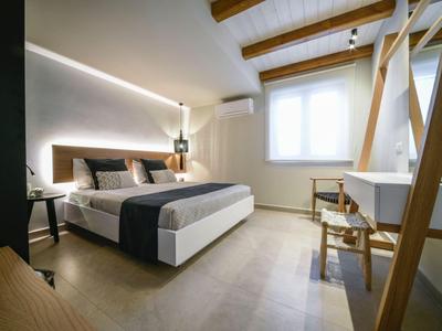 Dormitorio moderno con cama doble, vigas de madera en el techo y escritorio junto a la ventana.
