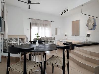 Habitación de hotel moderna con zona de comedor, rincón para sentarse y área de descanso elevada.