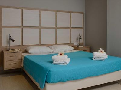 Lit double propre avec couverture turquoise et serviettes blanches dans une chambre d'hôtel moderne