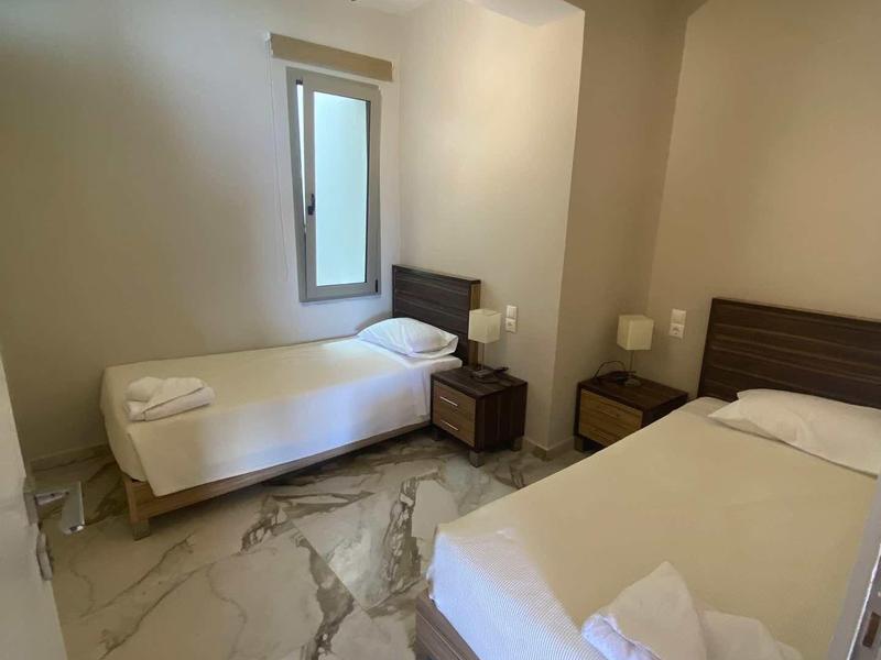 Chambre d'hôtel avec deux lits simples, table de nuit et fenêtre avec rideaux.