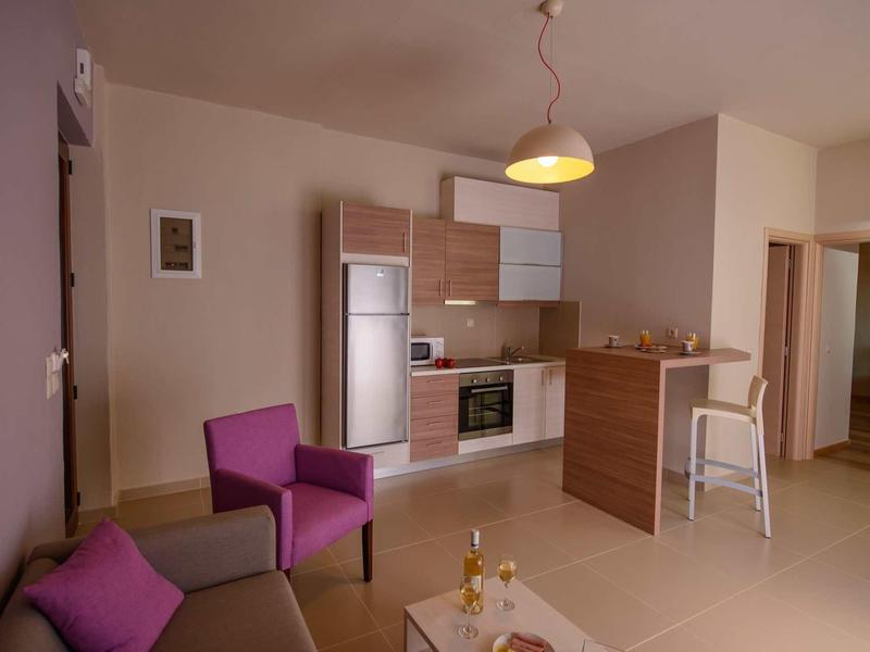 Espace de vie moderne avec kitchenette, sièges et table dressée aux tons chauds.