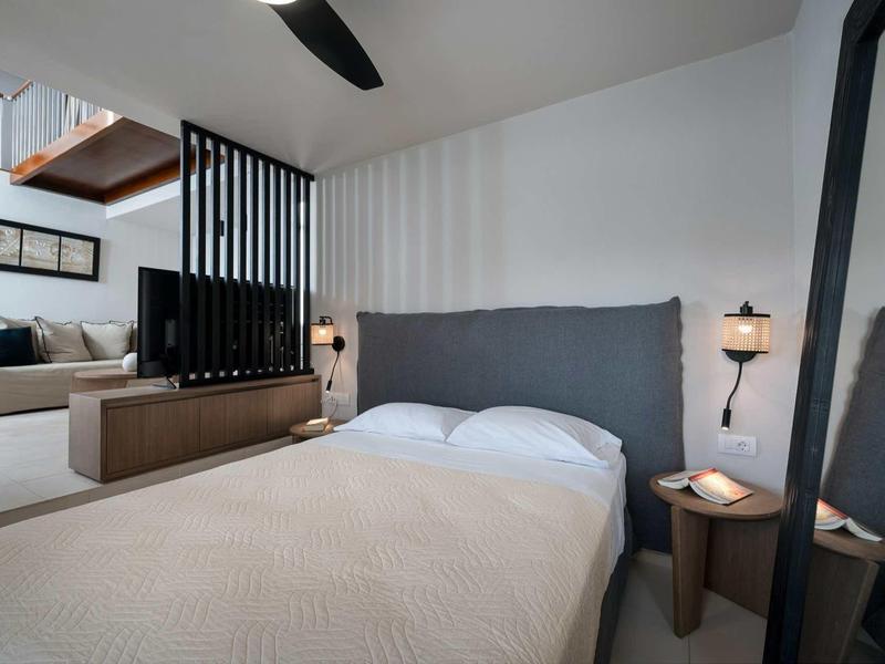 Chambre moderne avec grand lit, tête de lit grise et éclairage indirect