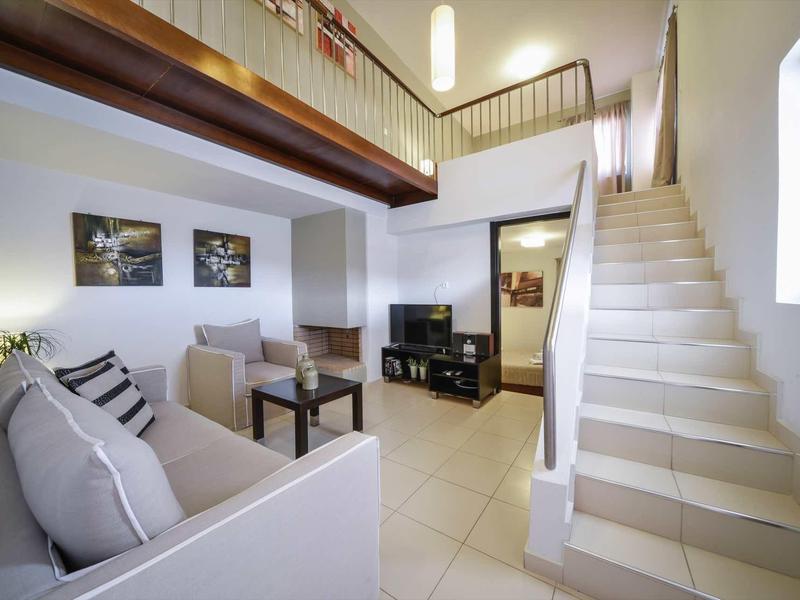 Salon lumineux avec escalier menant à l'étage supérieur et mobilier moderne.