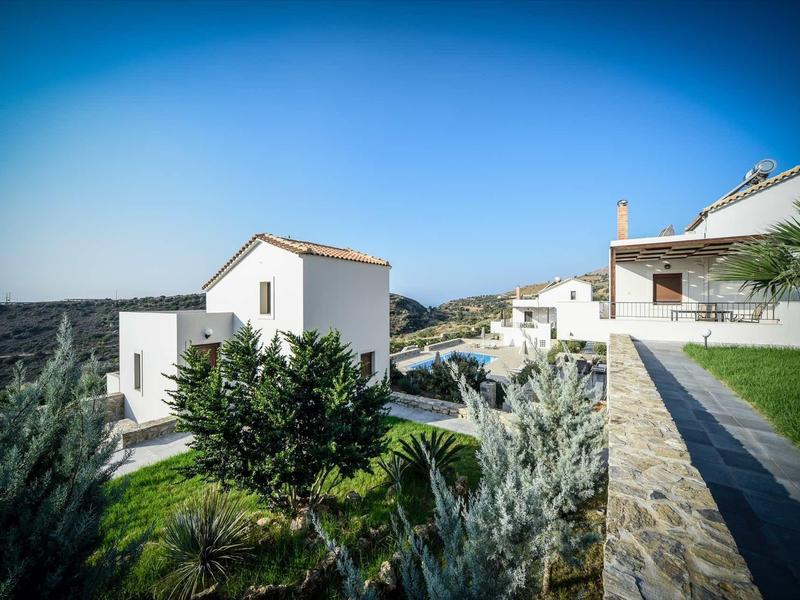 Maisons de vacances modernes avec jardin et terrasses en pierre sous un ciel bleu clair