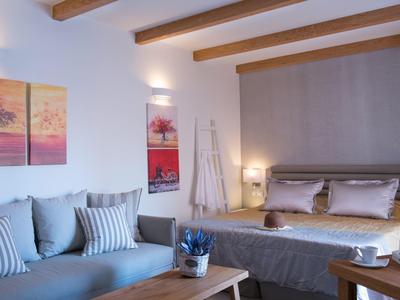 Cozy hotel room with bed, sofa, wooden beams, and decorative wall art.