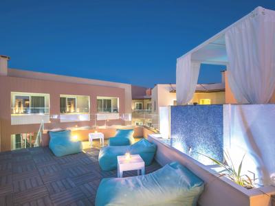 Osvětlená terasa s polštáři a závěsy pod jasnou večerní oblohou.