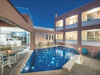 Moderní hotelový bazén s osvětlenou terasou a stoly za soumraku.