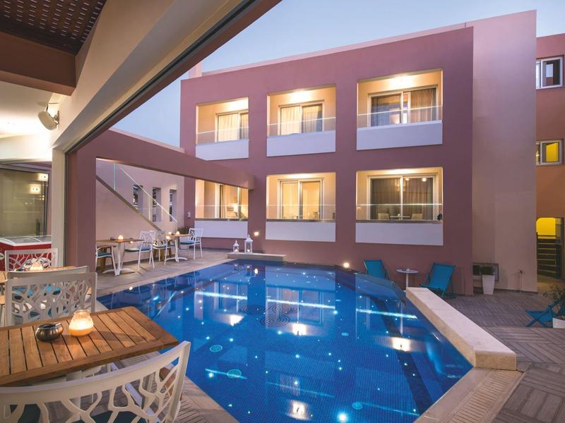 Modern hotel with an outdoor pool, patio seating, and rooms with balconies overlooking the pool area.