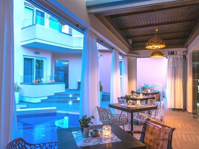 Cozy outdoor dining area beside a modern pool at twilight in a hotel setting.