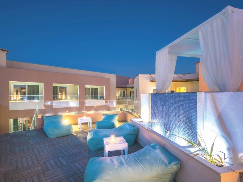Cozy rooftop lounge with blue bean bags and soft lighting under a clear blue sky.