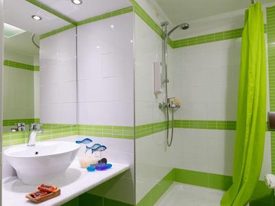 Nowoczesna łazienka z prysznicem, okrągłą umywalką, lustrem i jasnym zielonym zasłoną.