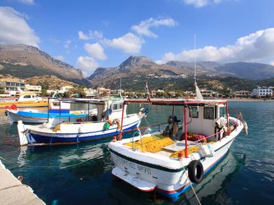 Kolorowe łodzie rybackie zacumowane w spokojnym porcie pod częściowo pochmurnym niebem.