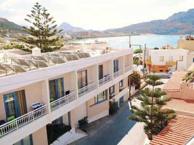 Moderner mehrstöckiger Gebäudekomplex mit Balkonen, umgeben von Bergen und mediterraner Landschaft.