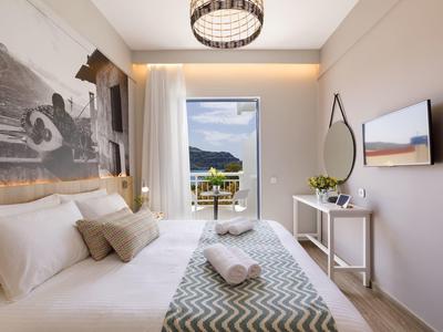 Jasny pokój hotelowy z łóżkiem, balkonem z widokiem na morze i nowoczesnym wystrojem.