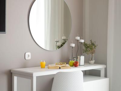 Nowoczesne biurko w hotelowym pokoju z okrągłym lustrem, krzesłem i dekoracjami.