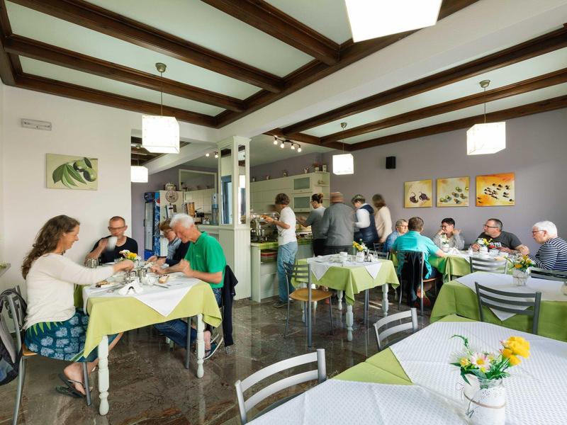 Jasna jadalnia z stołami i gośćmi jedzącymi posiłek.