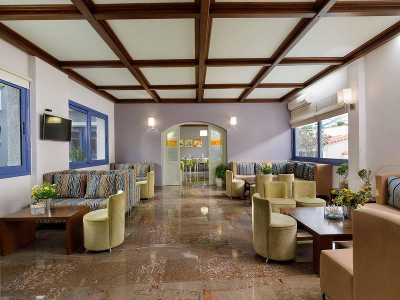 Przestronny salon hotelowy z fotelami, kanapami, stolikami i dużymi oknami.