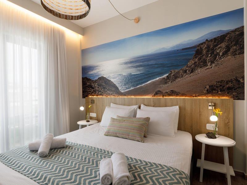 Nowoczesny pokój hotelowy z dużym łóżkiem i dużym muralem plaży na ścianie.