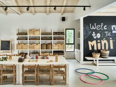 Jasny pokój zabaw dla dzieci z drewnianymi meblami, półkami i kolorowymi obręczami na podłodze.