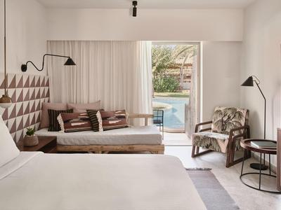 Nowoczesny pokój hotelowy z dużymi łóżkami, częścią wypoczynkową i dostępem do basenu.