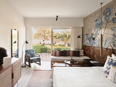Helles Wohnzimmer mit großem Fenster, Sofa, Couchtisch, Pflanzen und blau-grauer Blumenwand.