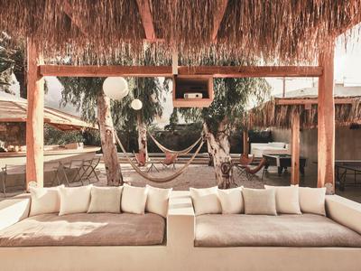 Gezellige lounge met beige banken en hangmatten onder een rieten dak in de buitenlucht.