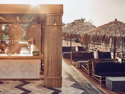 Bar sulla spiaggia accanto a lettini e ombrelloni di paglia al tramonto.