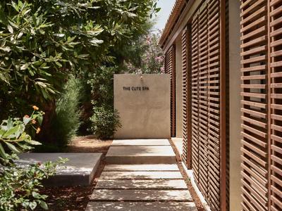 Nowoczesny korytarz hotelowy z drewnianymi żaluzjami i bujną zielenią wzdłuż ścieżki.