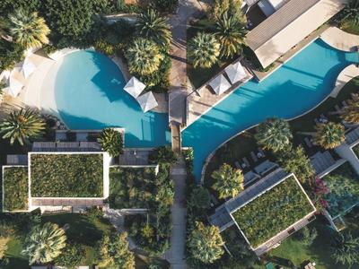 Vista aerea di un resort con due piscine e edifici circostanti con vegetazione.