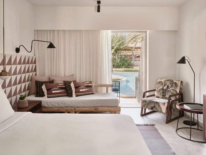 Nowoczesny pokój hotelowy z dużymi łóżkami, częścią wypoczynkową i dostępem do basenu.