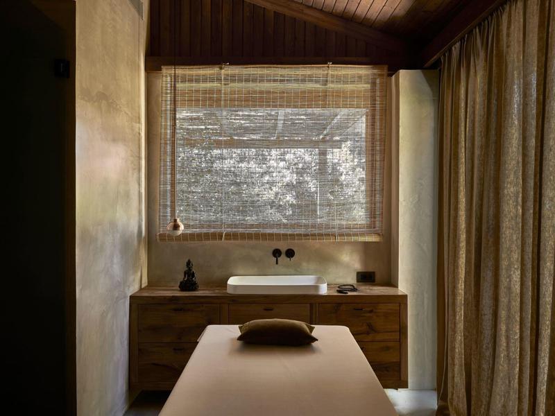 Rustykalny pokój spa z stołem do masażu, drewnianymi meblami, żaluzjami i zasłonami