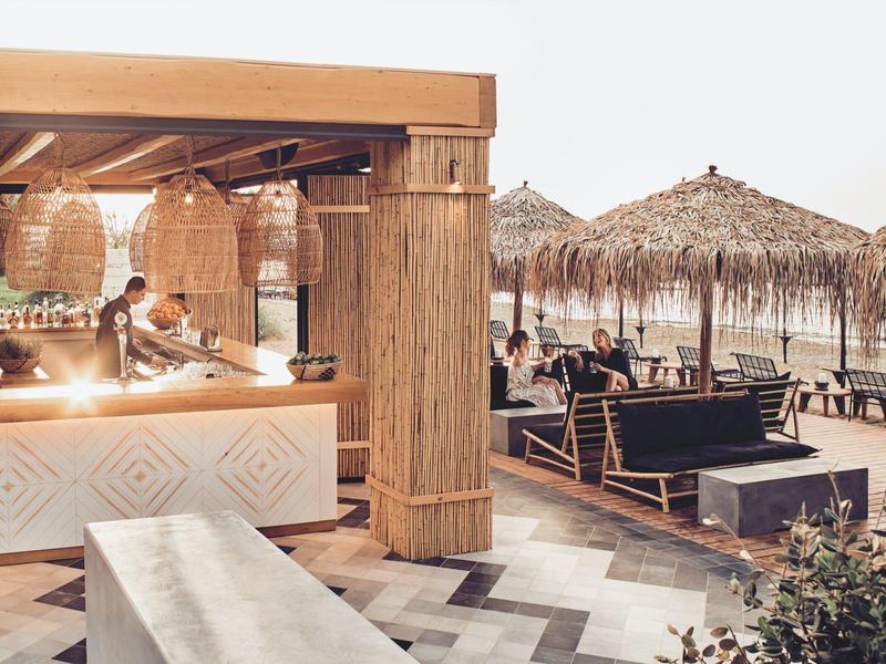 Otwarta plażowa strefa barowa z miejscami do siedzenia i dachami ze słomy nad morzem