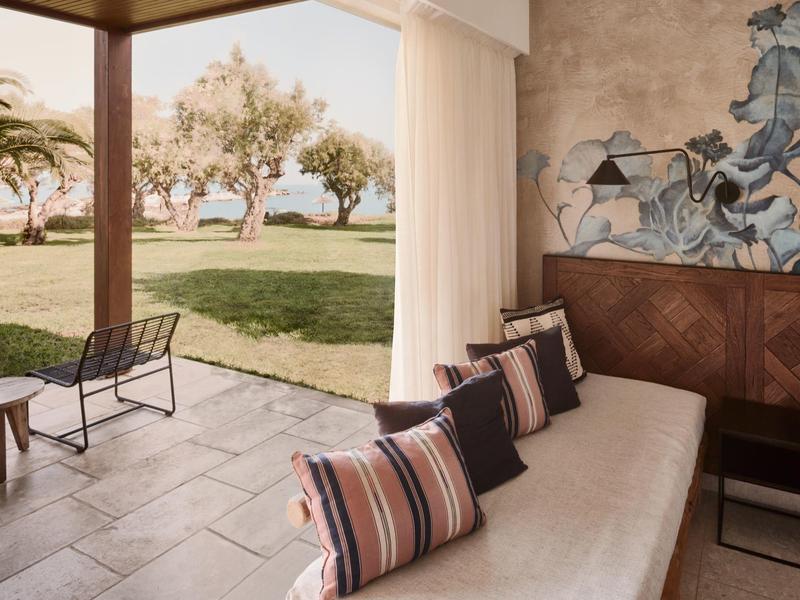 Nowoczesny salon z sofą i krzesłami z widokiem na zieloną przestrzeń na zewnątrz.