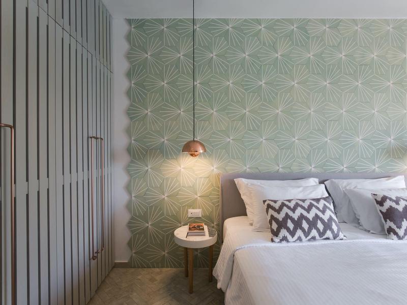 Sypialnia z tapicerowanym zagłówkiem, ścianą z wzorem i nowoczesną lampką nocną.