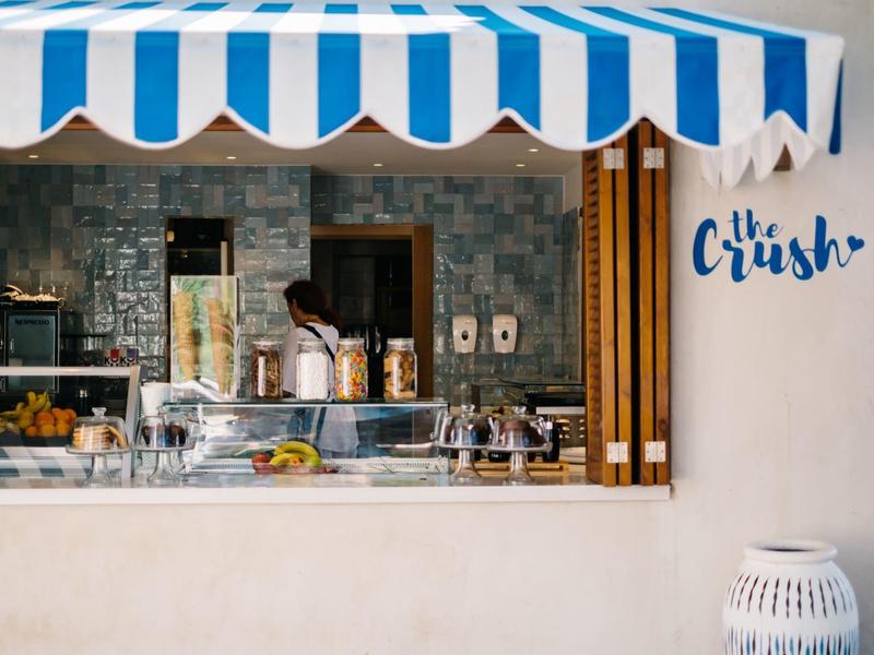 Otwarty kiosk z niebiesko-białymi markizami i wyciskarkami do soków w nowoczesnym otoczeniu