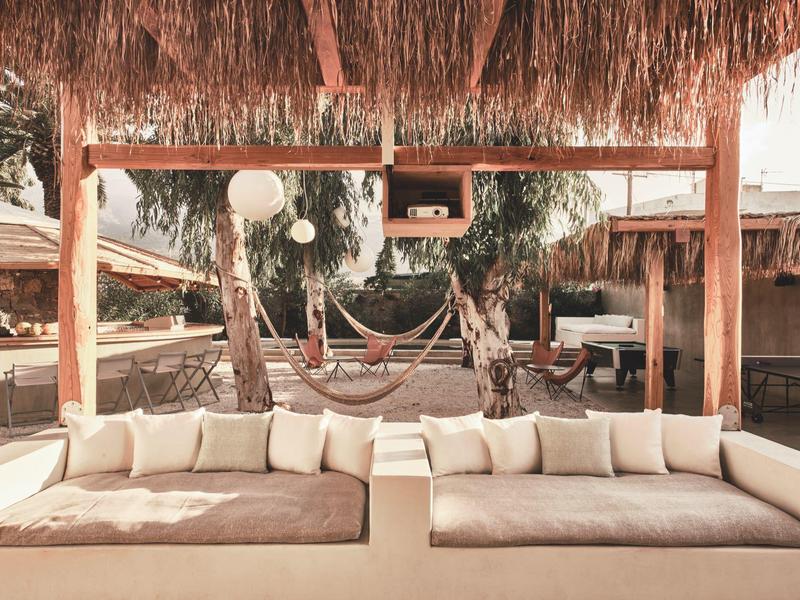Przytulny salon z beżowymi sofami i hamakami pod strzeżonym dachem na zewnątrz.