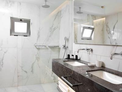 Moderne badkamer met marmeren tegels, dubbele wastafels en grote spiegels.