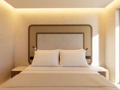 Modern slaapkamer met groot bed, hoofdeinde en zachte wandverlichting.