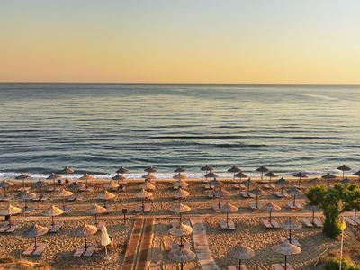 Zonsondergang op het strand met rijen parasols en kalme zee