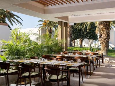 Freiluftrestaurant mit gedeckten Tischen und üppiger grüner Vegetation in einem Hotelgarten.