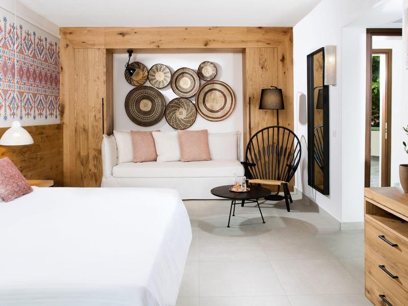 Lichte hotelkamer met houten meubels, wanddecoraties en een gezellige zithoek.