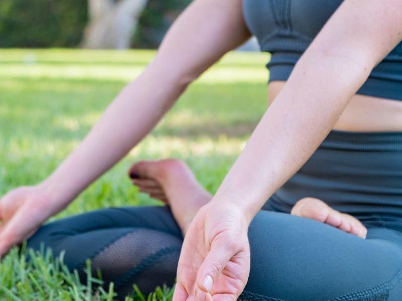 Persoon zit gekruist op gras en mediteert buiten
