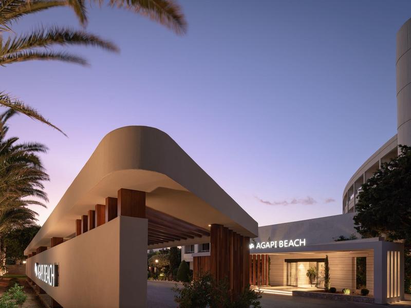 Moderne hotelentree met gebogen dak en palmbomen bij schemering